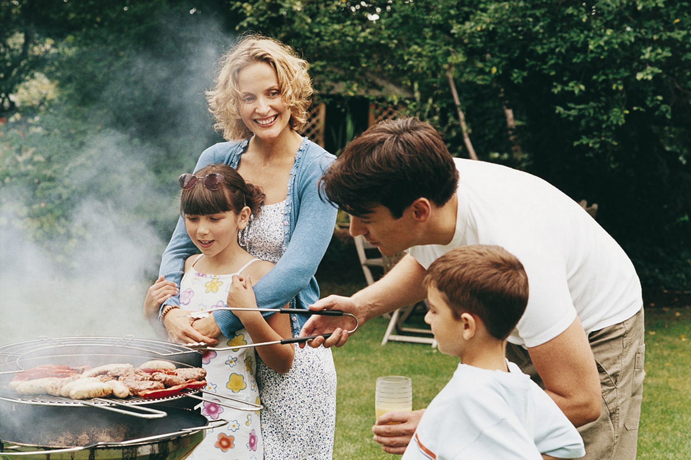 Family-cooking-a-barbecue-in-their-garden